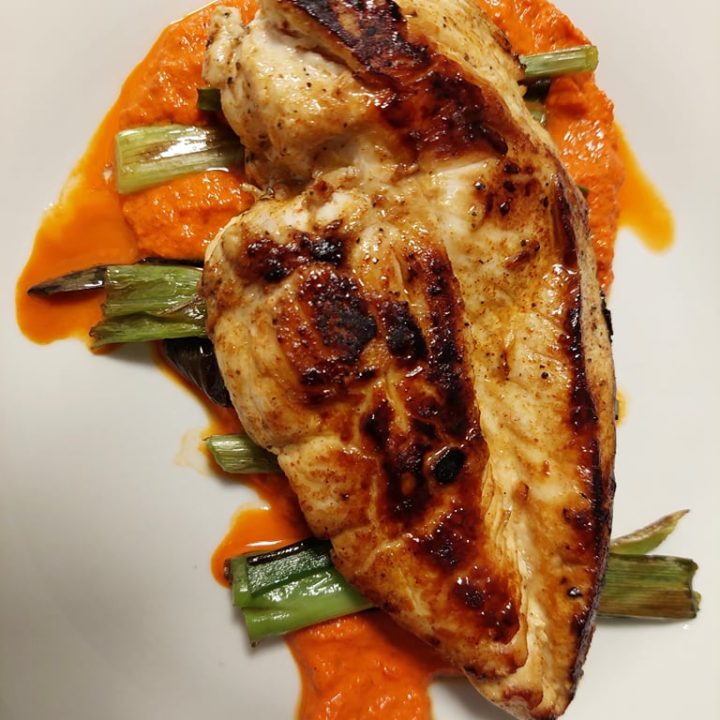 Chicken with grilled spring onions and romesco sauce